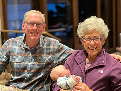 Greg and Nancy Serrurier sit together holding their baby grandson, Bracy