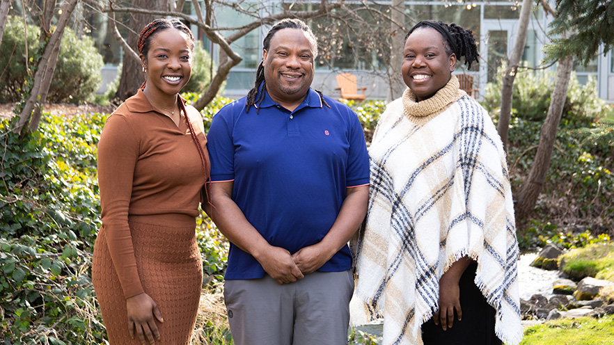 Three professors stand together in an outdoor location.