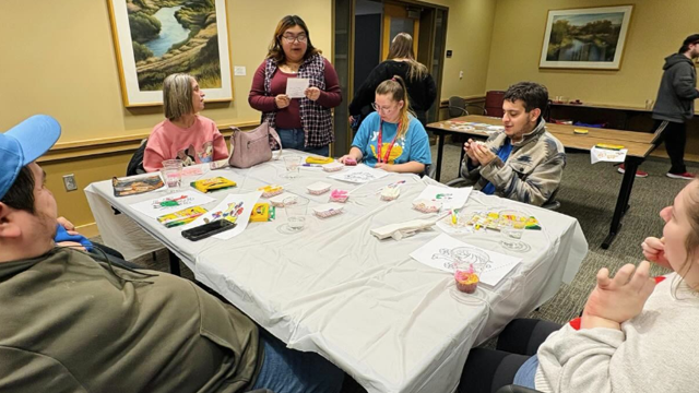 A group of people around a table with craft supplies.
