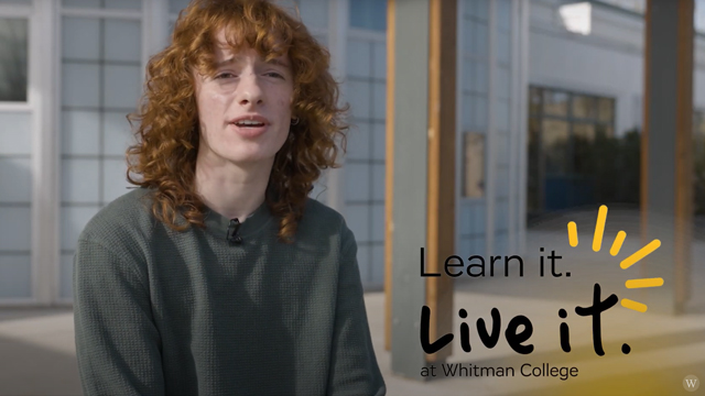 Portrait of Caine Ryan, with shoulder-length curly hair. Black text reads: “Learn it. Live it. at Whitman College”.