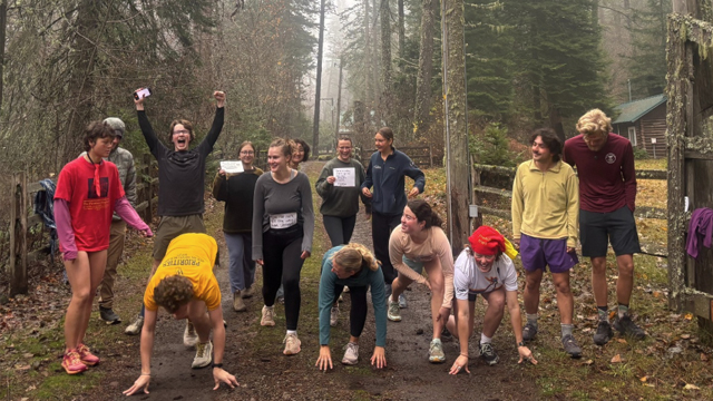 A group of students lining up to race on a road in the forest.
