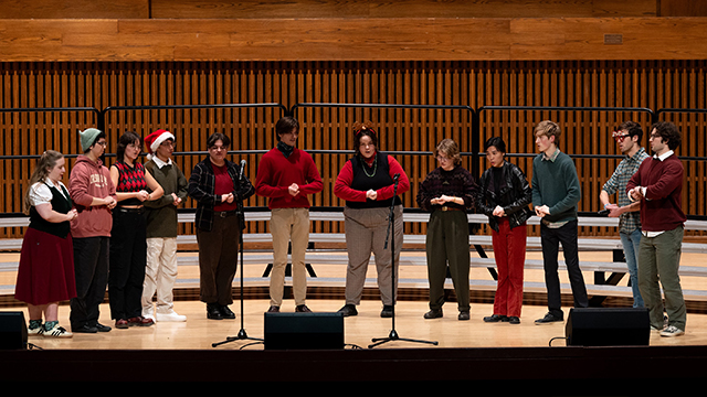 A line of students singing on the Cordiner Hall stage.