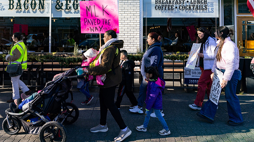 A group of people with signs march past a downtown Walla Walla business on Martin Luther King Jr. Day 2025.