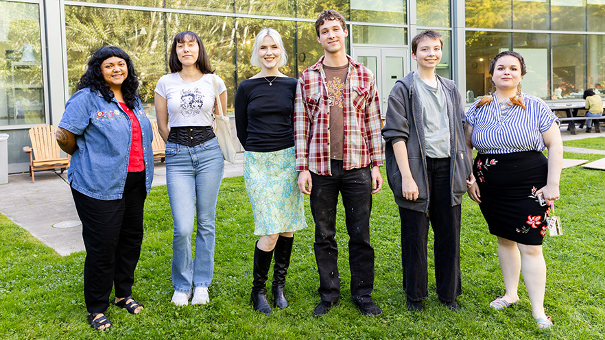 Six students standing in grass, with Fouts Center for Visual Arts in the background.