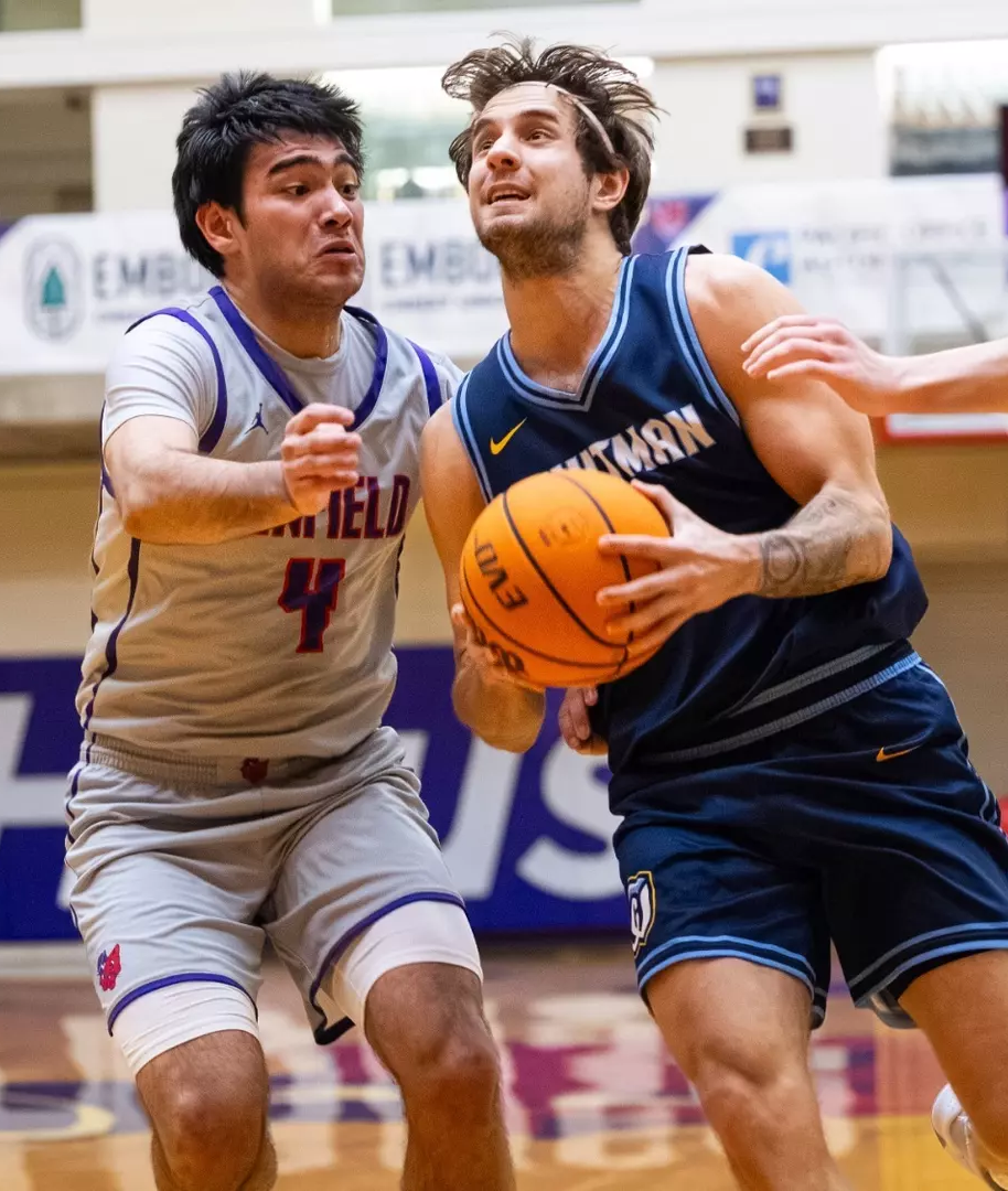 A Whitman basketball player and Linfield basketball player going head-to-head