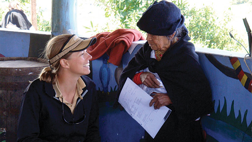 Anna Taft (left) smiles at an older person in front of her who is holding a piece of paper.