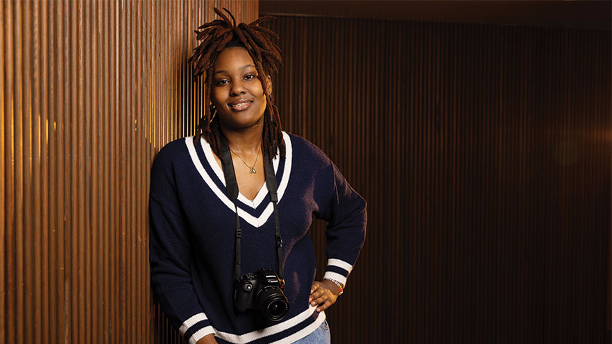 Portrait of Asya Johnson ’26 standing with a camera hanging from her neck.
