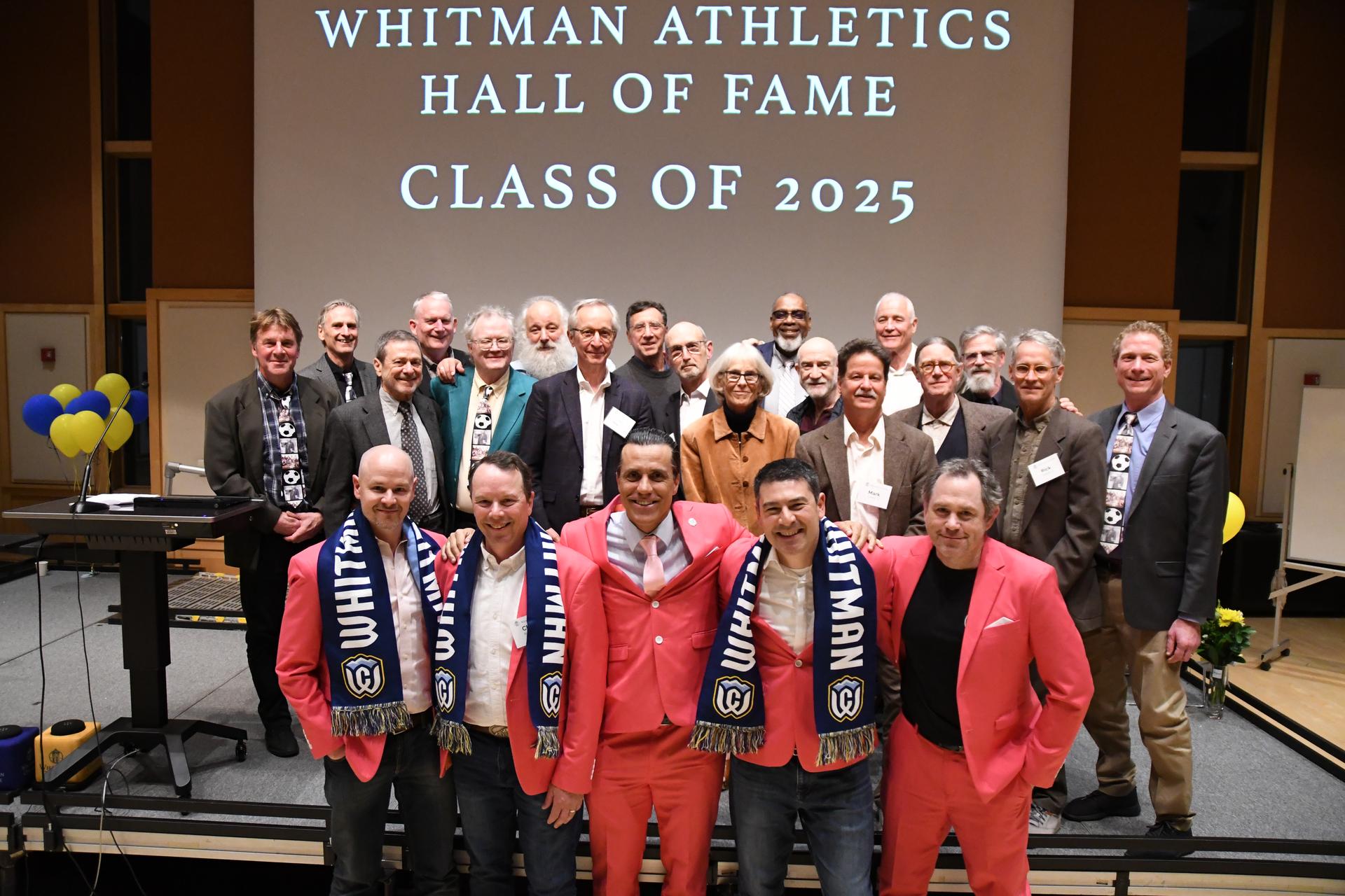 A group of people posing on a stage. Behind them reads ''Whitman Athletics Hall of Fame, Class of 2025''