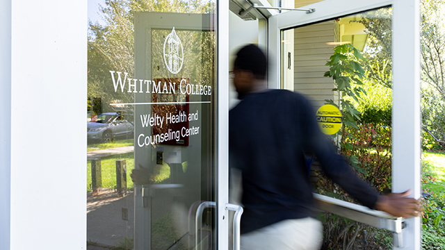A person walking through the entrance of Welty Health and Counseling Center.