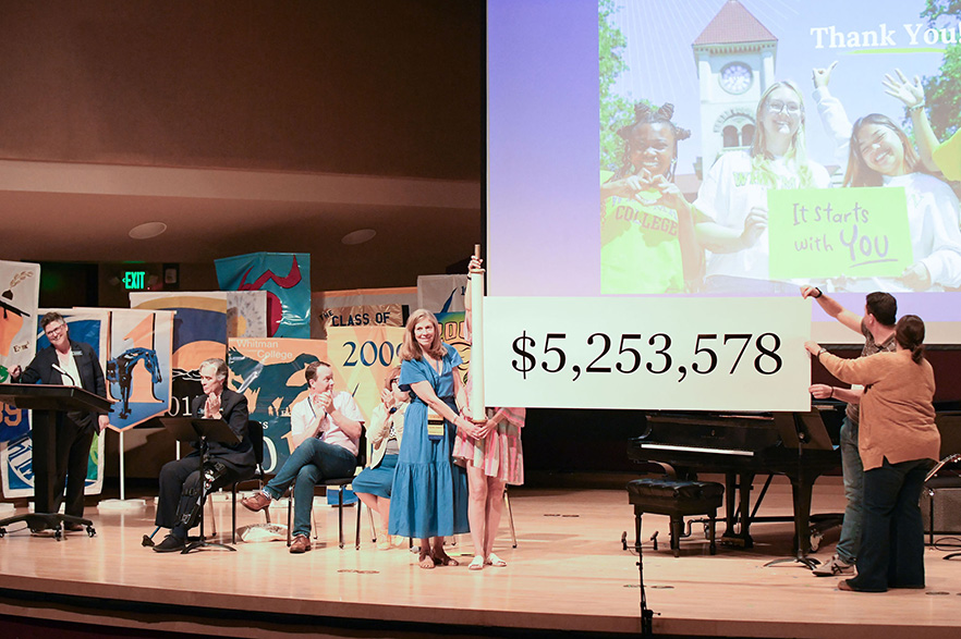 People on stage holding a scroll reading a grand total of $5,253,578 donations at Whitman’s Reunion Convocation.
