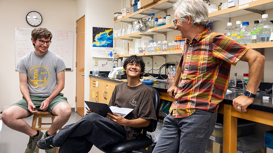Two students and a teacher in a lab setting.