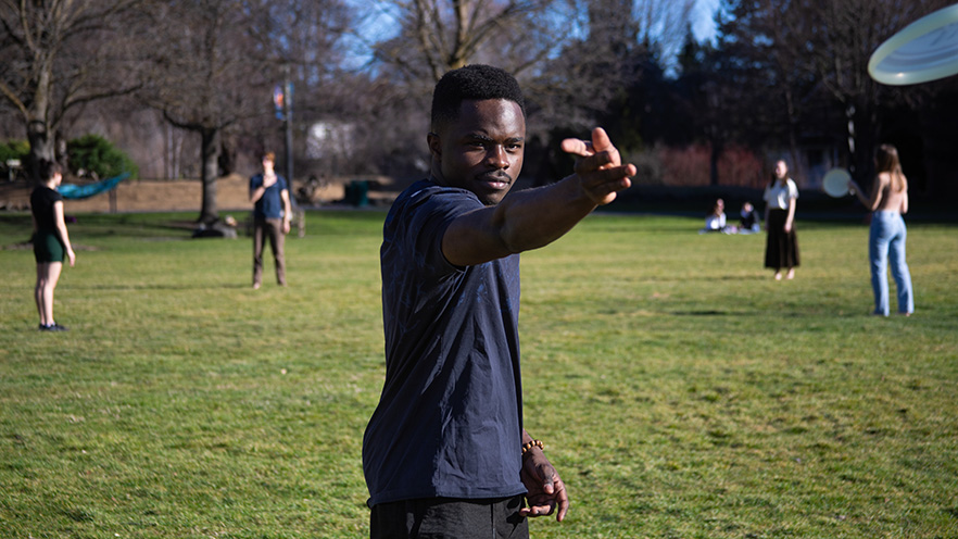 Patrick Mulikuza throws a frisbee past the camera.