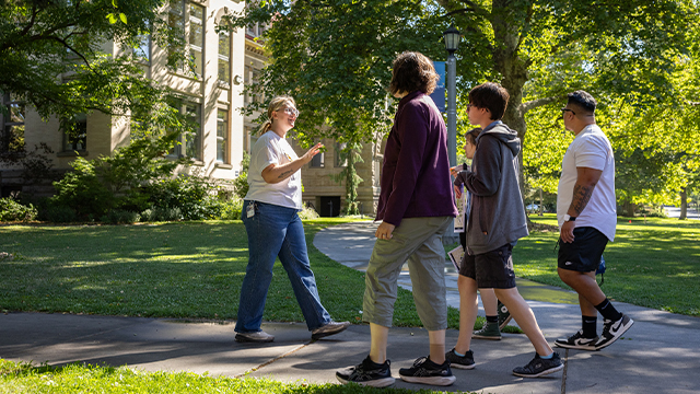 A tour guide and a group of four visitors to campus with Memorial Building in the background.
