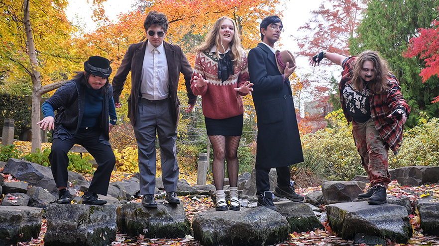 Five students strike poses while standing on boulders.