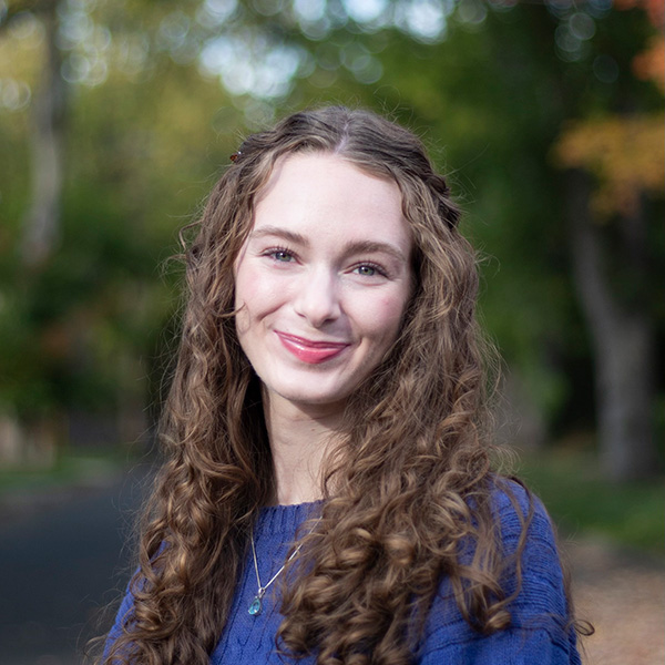 A woman smiling in a portrait with a blue sweater on