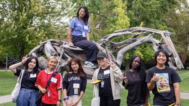 A group of students pose with Styx, a sculpture that looks like a horse made of driftwood.