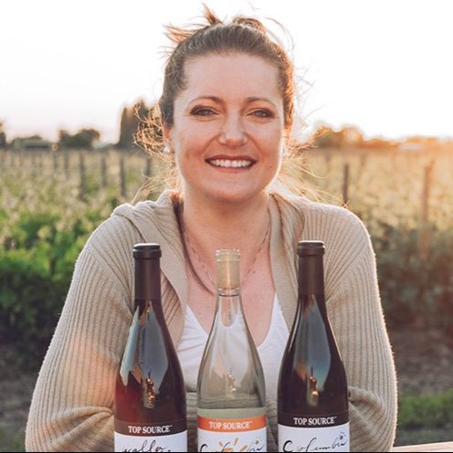 Meredith Hyslop posing with wine bottles at an outdoor table