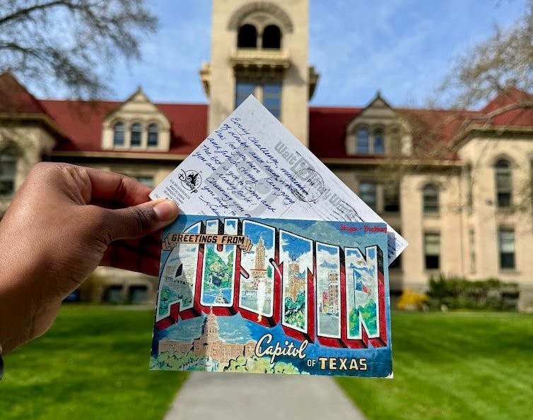 The front and back of a postcard being held up in front of Memorial Buidling 