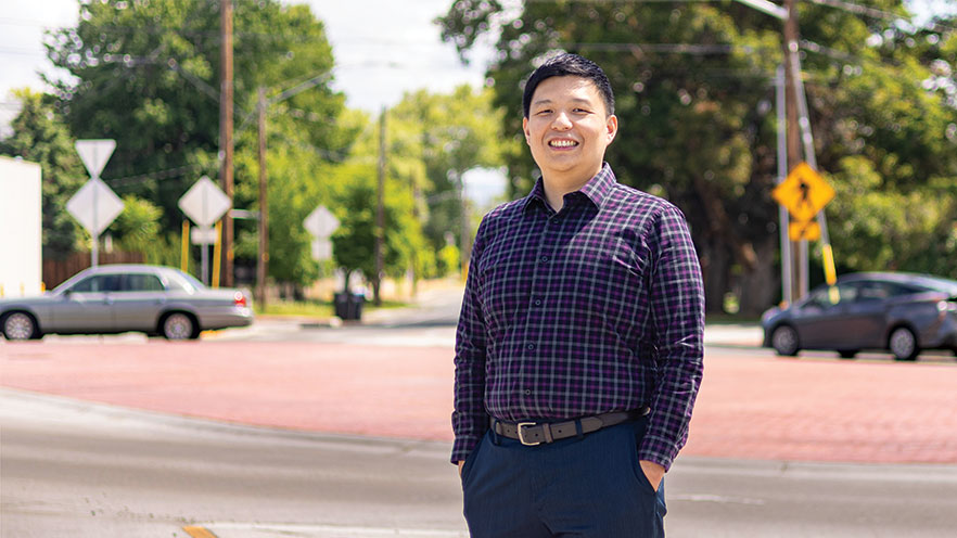 Assistant Professor of Economics Wisnu Sugiarto stands in front of a roundabout at an intersection near campus.