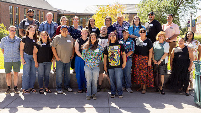 A large group of students and staff members pose for an outdoor photo on the campus of Whitman College.
