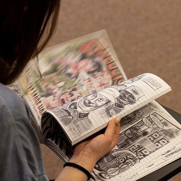 alt=''Whitman College student flipping through a graphic novel.''