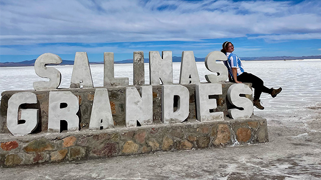 Max Lewis ’29 sits on the side of a monument with large letters: “Salinas Grandes”