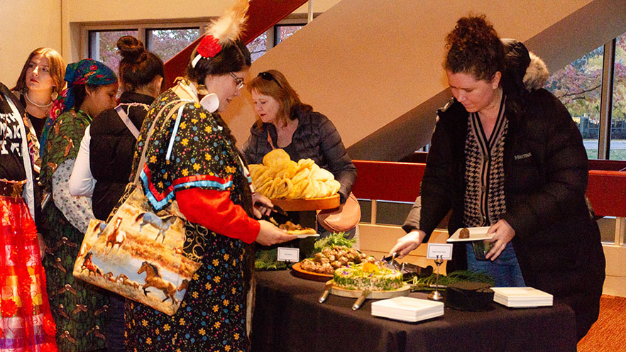 A group of people filling their plates from a buffet table.