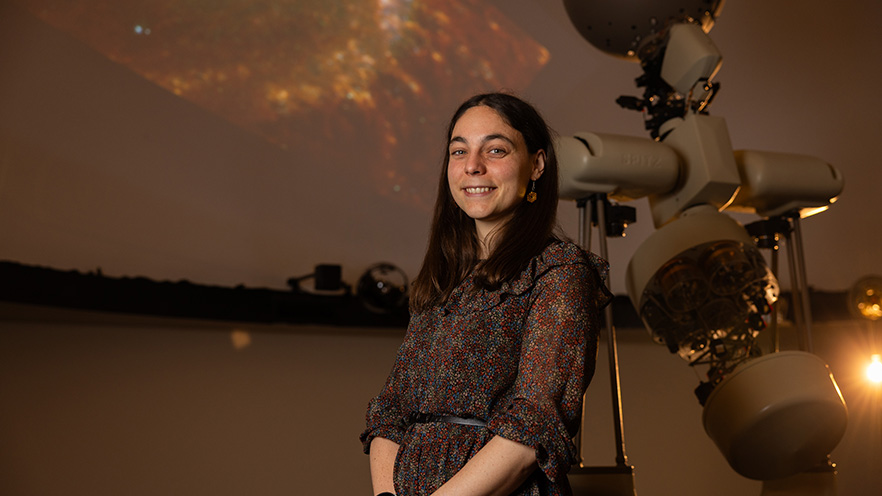 Jessica Sutter stands next to a large piece of equipment inside Whitman’s planetarium.