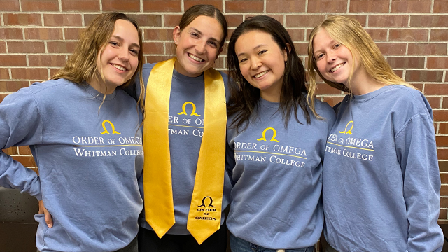 Four student leaders wearing matching Order of Omega, Whitman College shirts.