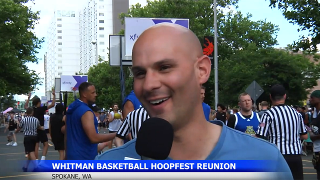 News segment screenshot with John Lamanna speaks into a reporter’s microphone with basketball players and referees visible in the background.