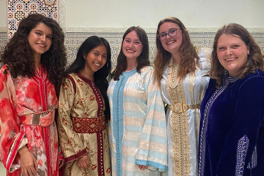 A group of five people pose for a photo in colorful outfits.