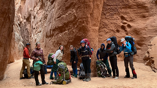 A group of eight people with backpacking gear.