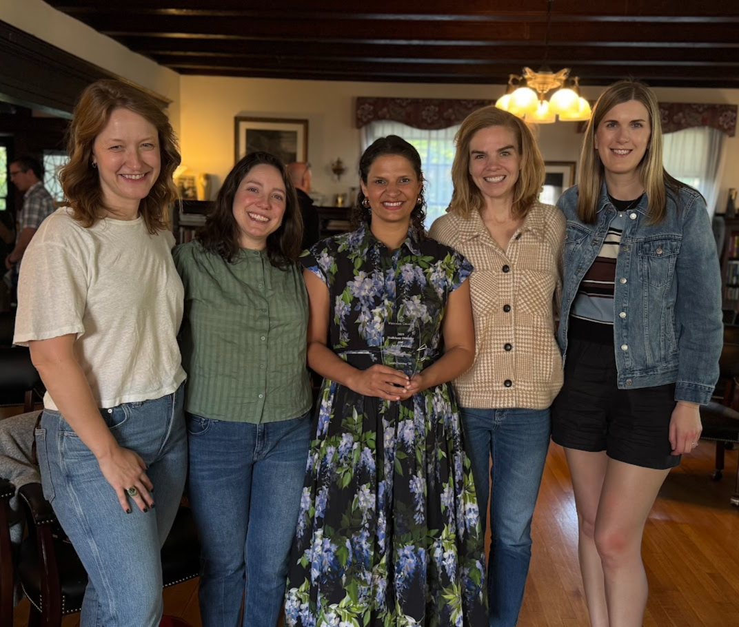 Sarah Deming holding her alumni award with friends 