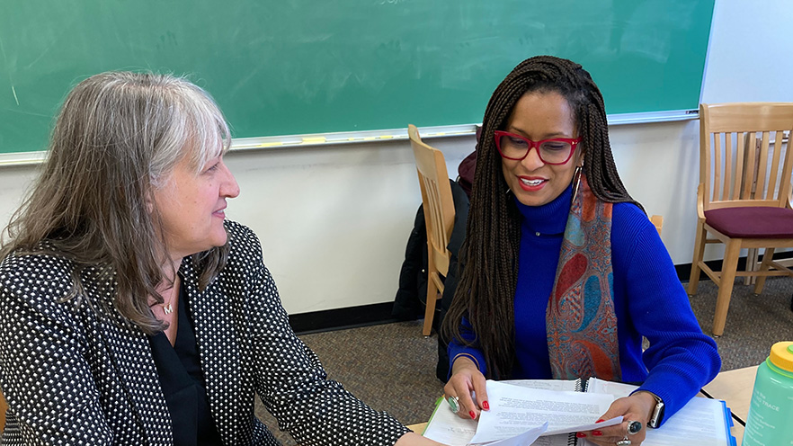 Michelle Janning (left) and Lu Austin (right) have a discussion over some papers in hand.