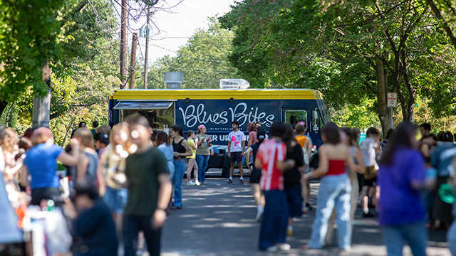 A crowd of students on the street in front of the “Blues Bites” food truck.