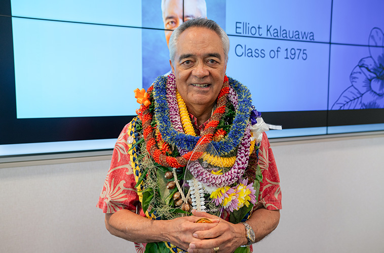 Elliot Kalauawa wearing many flower leis around his neck.