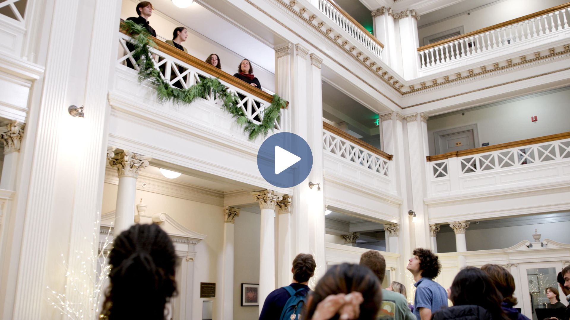 Four singers at a balcony with a crowd standing below.