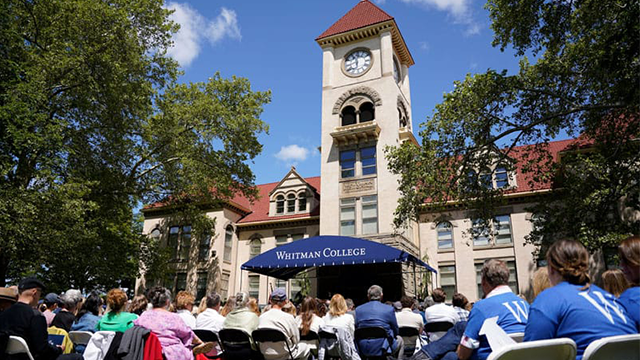 People sit in folding chairs in front of Memorial Building.