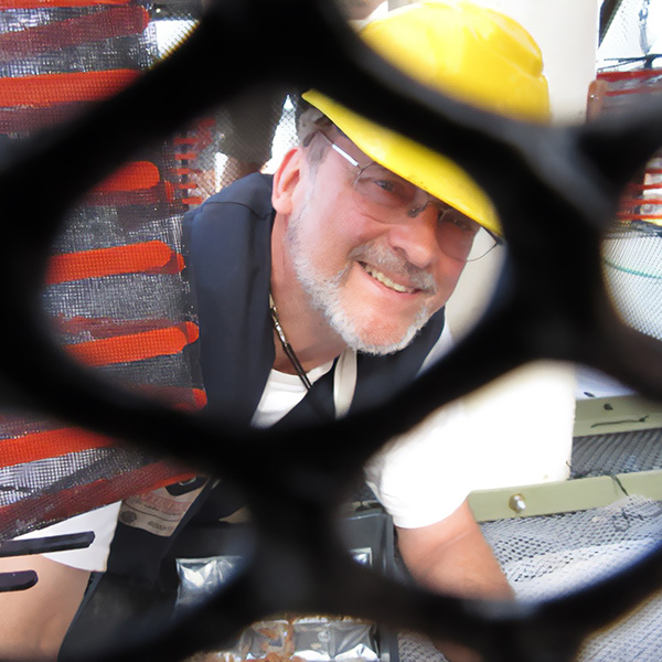 Paul Yancey, wearing a yellow hard hat, looks through a fish net