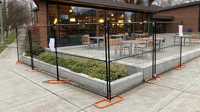 Black temporary fencing in front of the outside patio of Cleveland Commons
