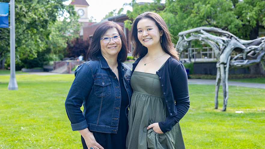 Ahn Lee Horn ’91 and Nina Horn ’25 stand on Ankeny Field with Memorial Building and Styx in the background.