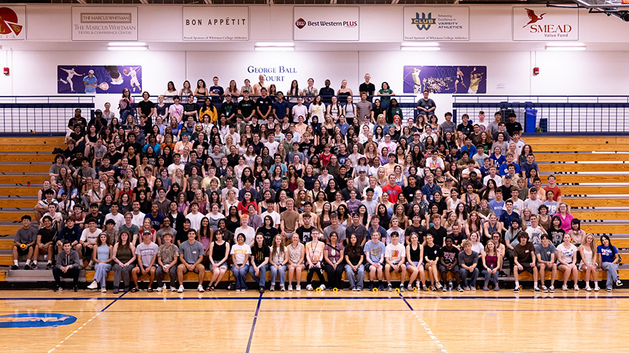 New students and the Class of 2029 sit together on bleachers in front of a basketball court.
