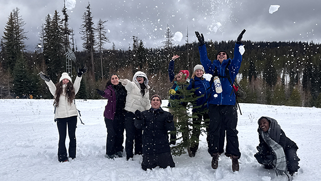 A group of happy students throwing snow into the air.