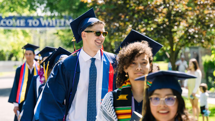 A line of students walking in graduation regalia.