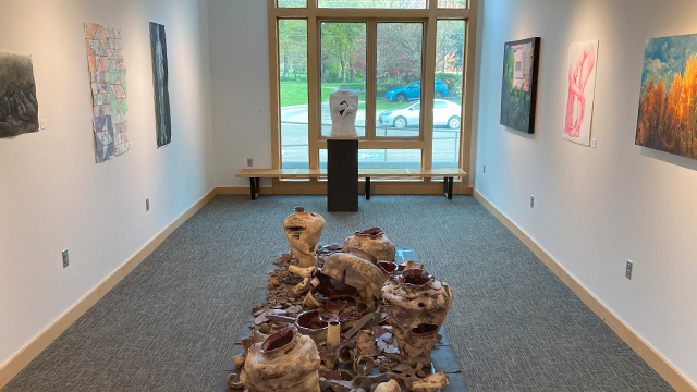 A small gallery space with several pieces of art on the walls and two sculptures on the floor.