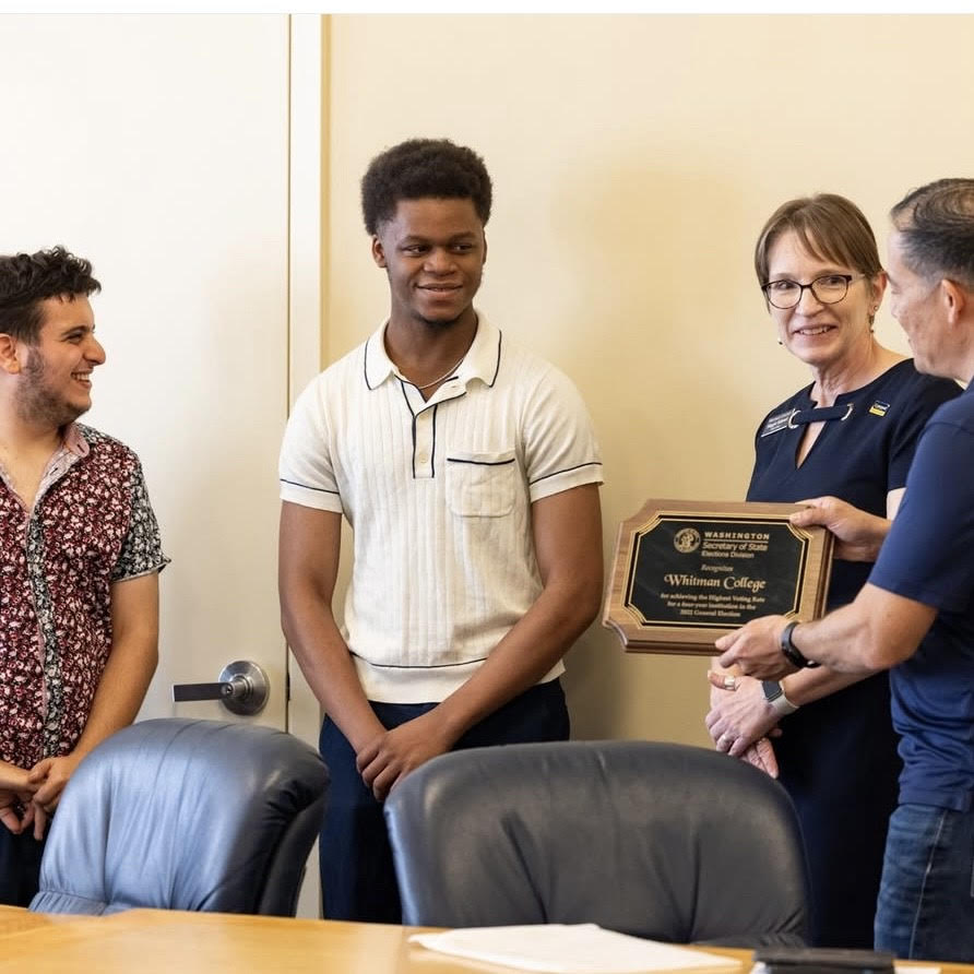Jonathan Becker '26, Vinson Russel '28 and Maggie Earhart accept a plaque from WA Secretary of State Steve Hobbs 