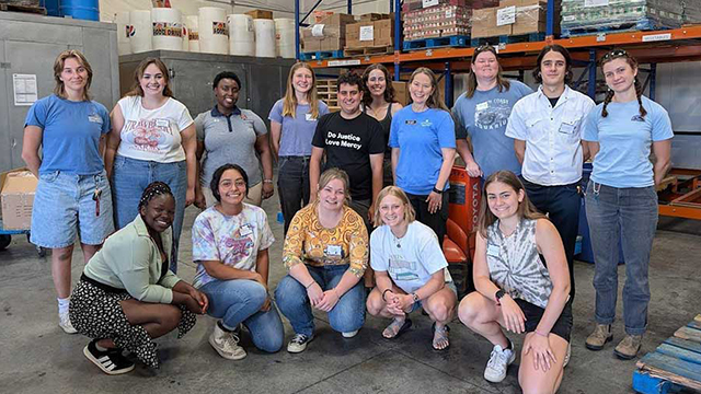 A group of volunteers pose for a photo in a warehouse setting.