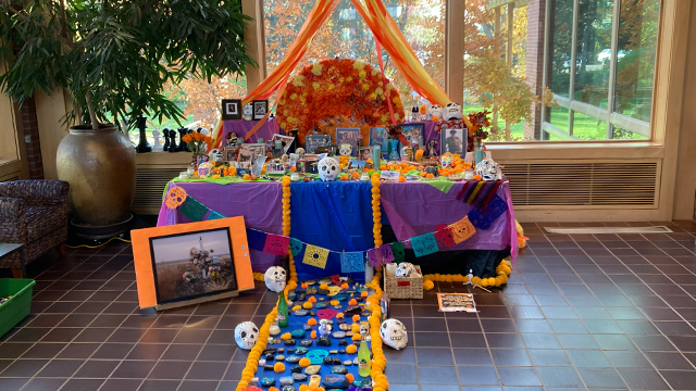 A colorful altar in the Reid Campus Center lobby covered with flowers, photographs and other mementos.