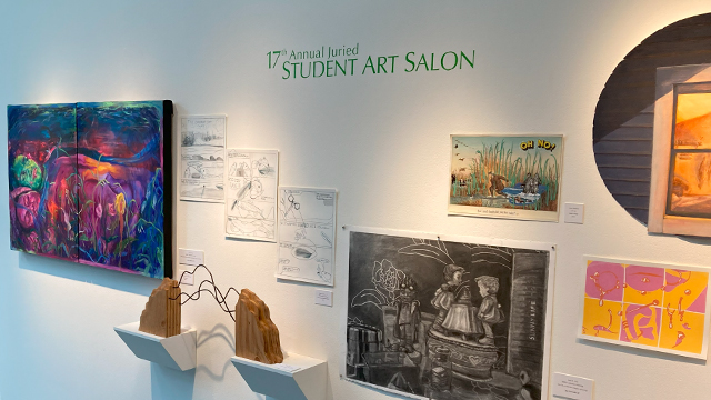 An assortment of artwork displayed on a white wall with green text: “17th Annual Juried Student Art Salon.”