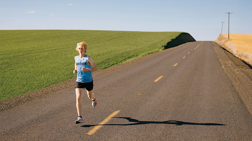 Jack McManus runs down a rural road with fields in the background.